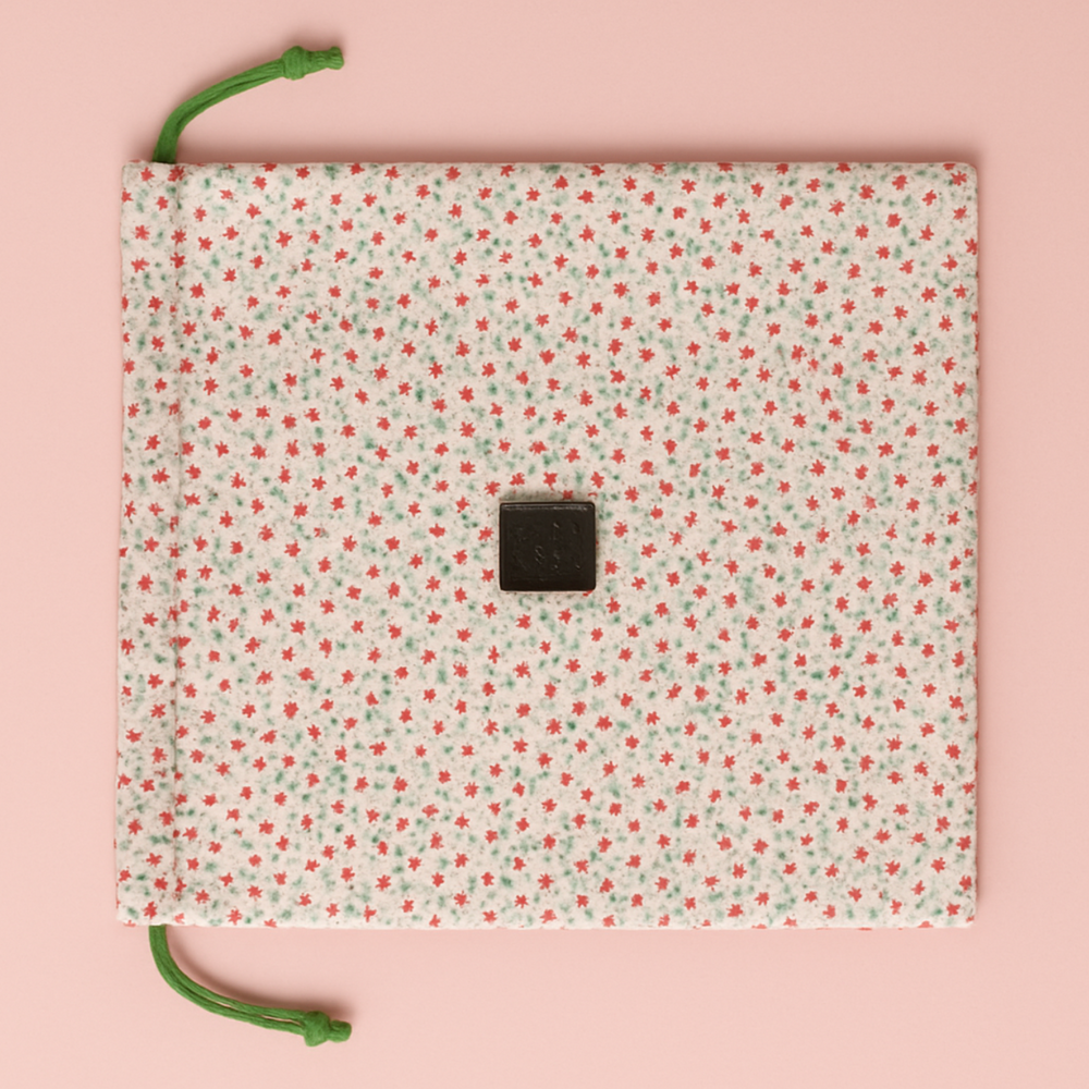 Floral-patterned pouch with green drawstrings on a pink background