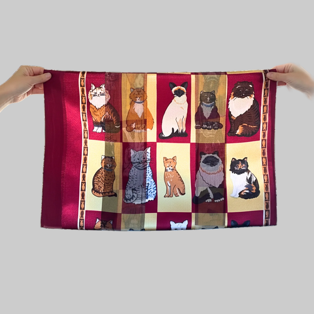 Towel with cat pattern held by two hands on a white background