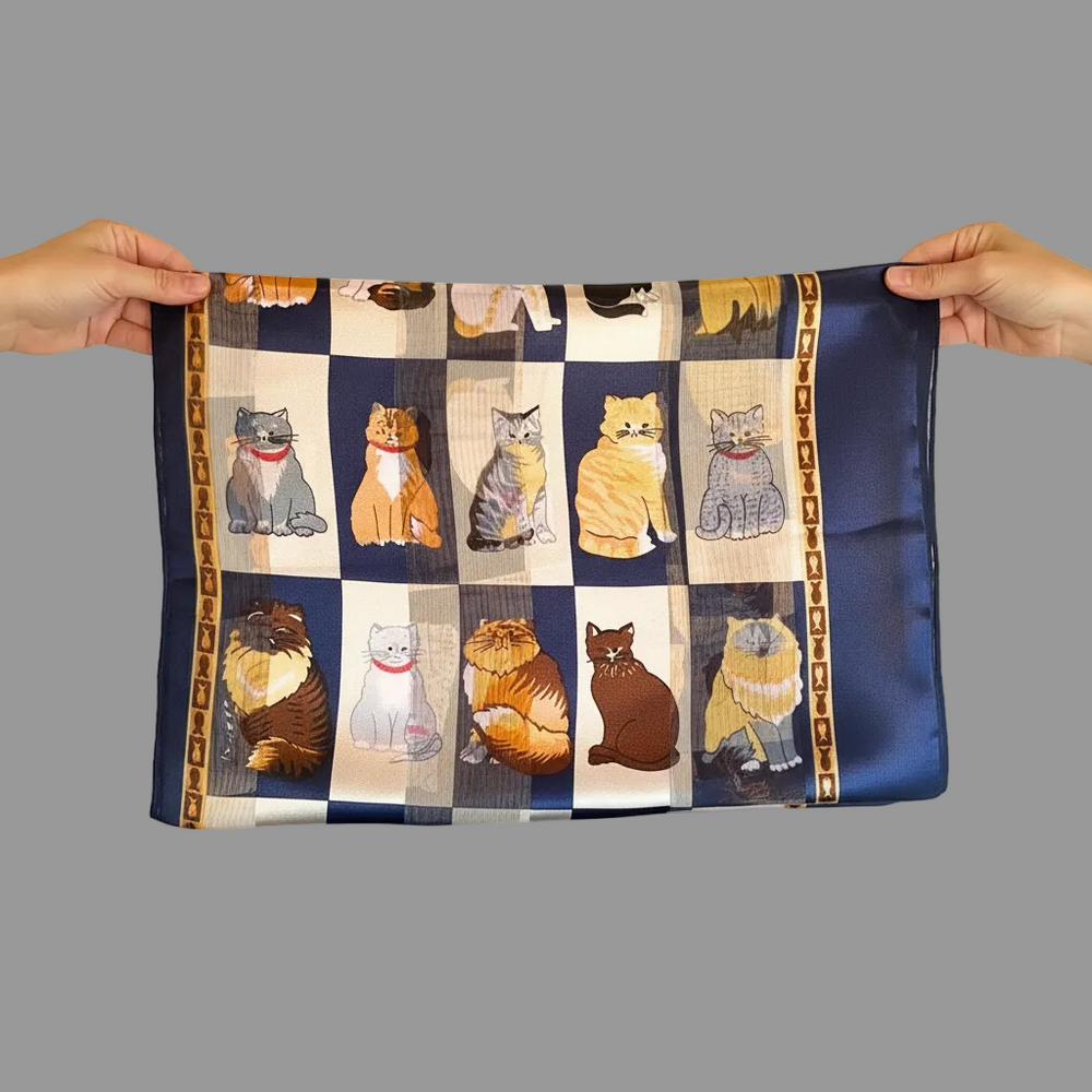 Satin scarf with cat pattern held by two hands against a gray background