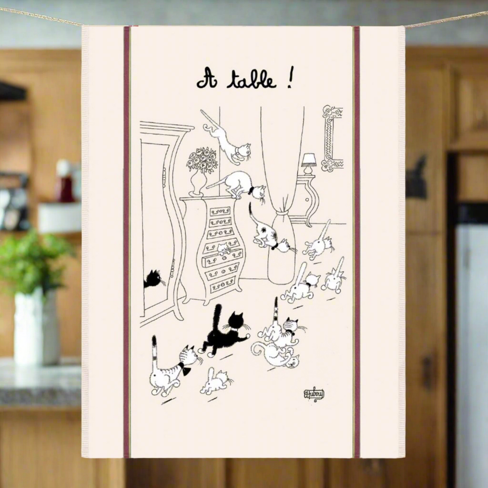 Tea towel with black and white cat illustration and 'A table!' text on a beige background