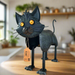 A set of metal garden figurines shaped like cats in various colors including black, ginger, tabby grey, and Siamese, each with a standing pose.