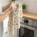 Patterned tea towel with illustrations of cats on a beige background