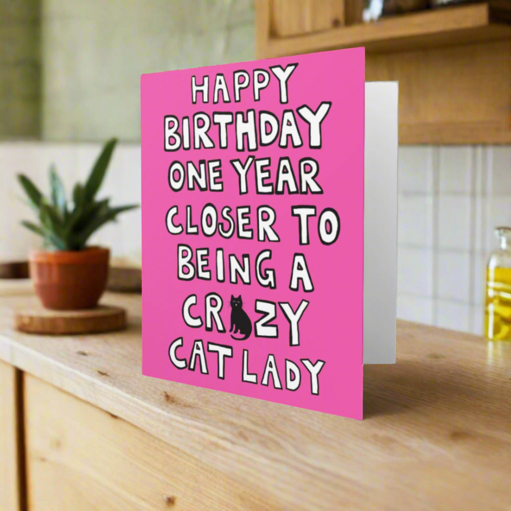 Pink birthday card with text and a cat illustration on a white background