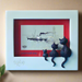 A rectangular white picture frame featuring an embossed and colored design with a 3D effect, depicting cats in front of a framed picture of a boat and lighthouse. The frame is made of glass and resin, with a hand-painted finish.