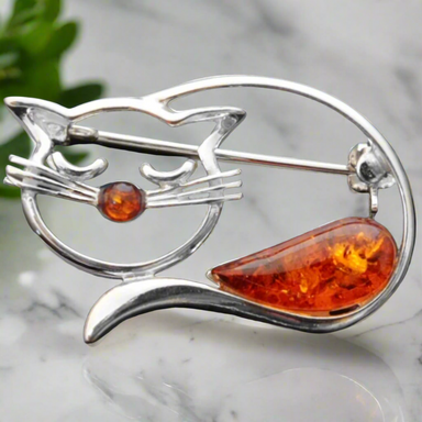 A silver brooch in the shape of a cat, featuring genuine Baltic amber as a highlight on the face.