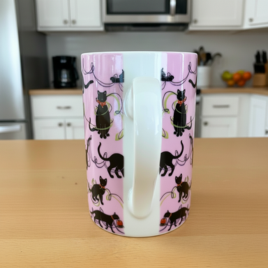 Mug with black cat pattern on a pink background on a wooden surface.