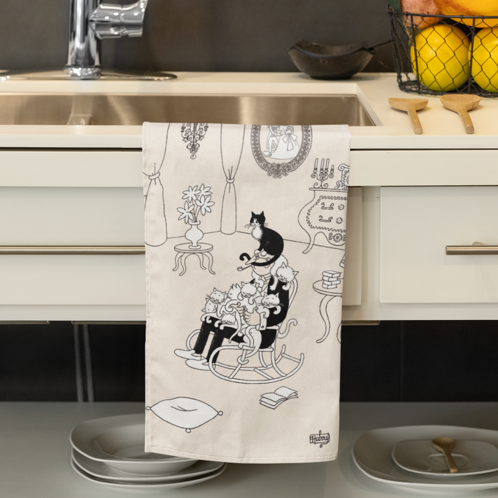 Decorative kitchen towel with black and white cat design hanging over a kitchen sink.