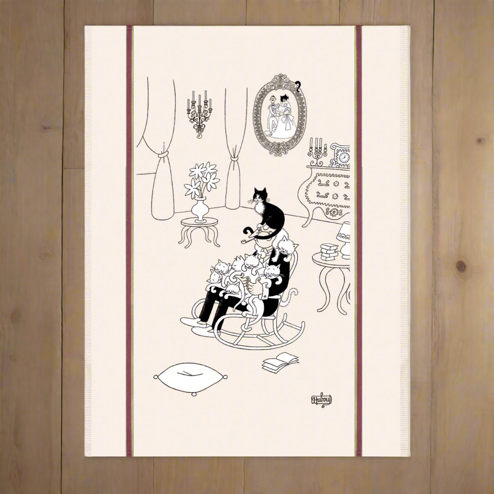 Decorative tea towel with black and white illustrations of a cat in a chair, table, and mirror on a beige background.