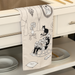 Decorative kitchen towel with cat illustrations hanging on a cabinet.
