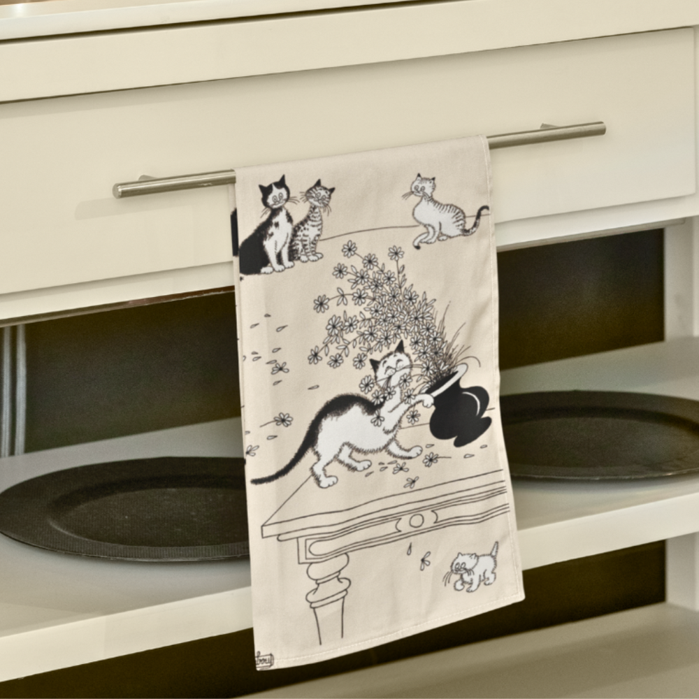 Decorative towel with cat designs hanging on a cabinet.