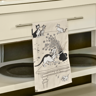Decorative towel with cat designs hanging on a cabinet.