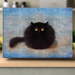 A colorful fridge magnet featuring a stylized black cat with a blue and pink background.