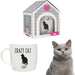A ceramic mug with a black cat and paw print pattern, text 'CRAZY CAT LADY' on the front, accompanied by a cat house-shaped gift box and a real cat looking at the camera.