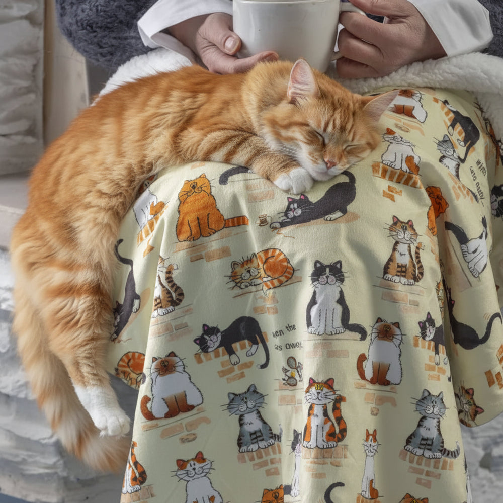 Person wrapped in a blanket with cat pattern holding a mug.