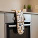 Oven mitt with dog pattern hanging on a kitchen oven
